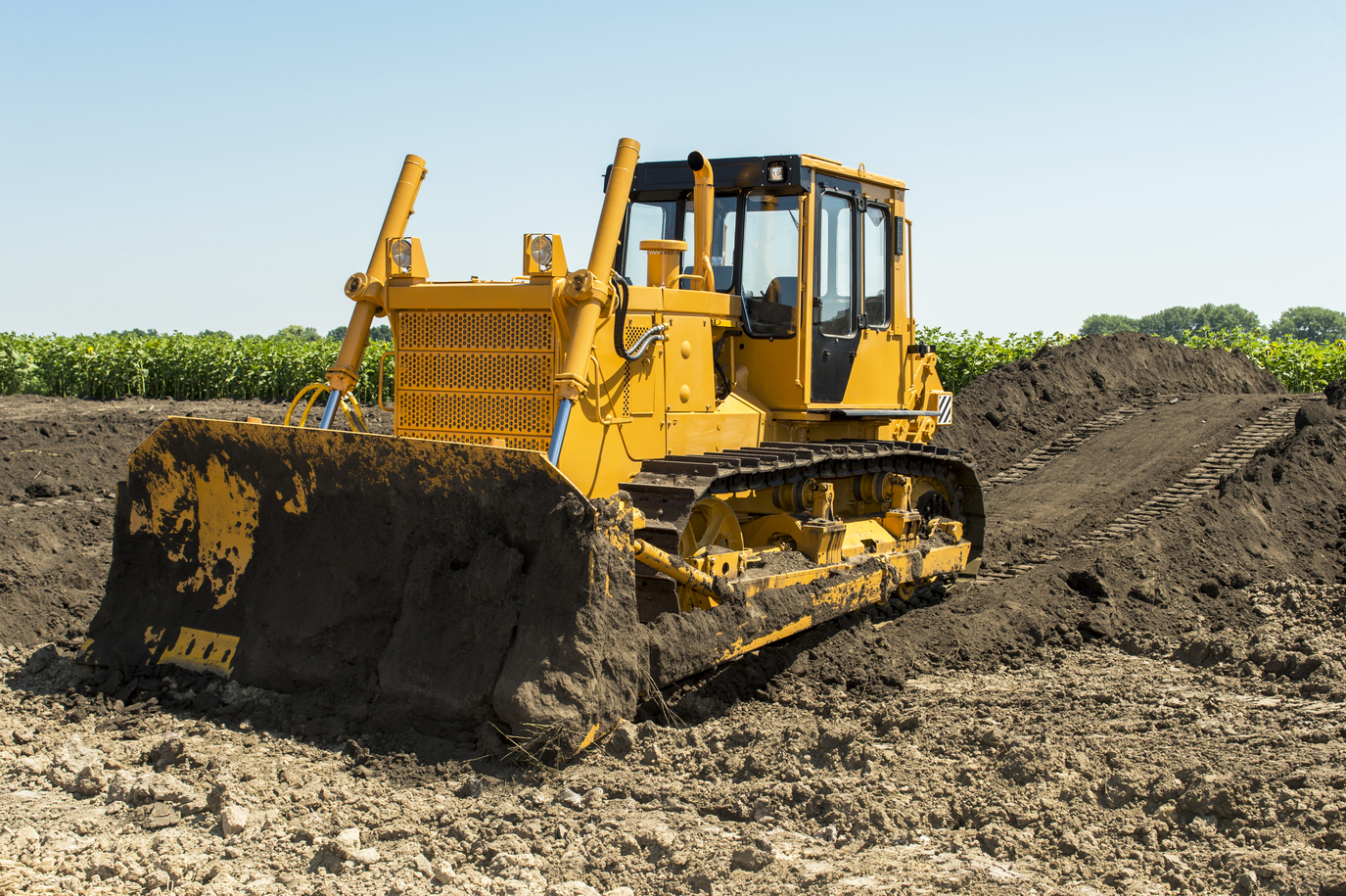 yellow bulldozer with crawler tractor standing in a field