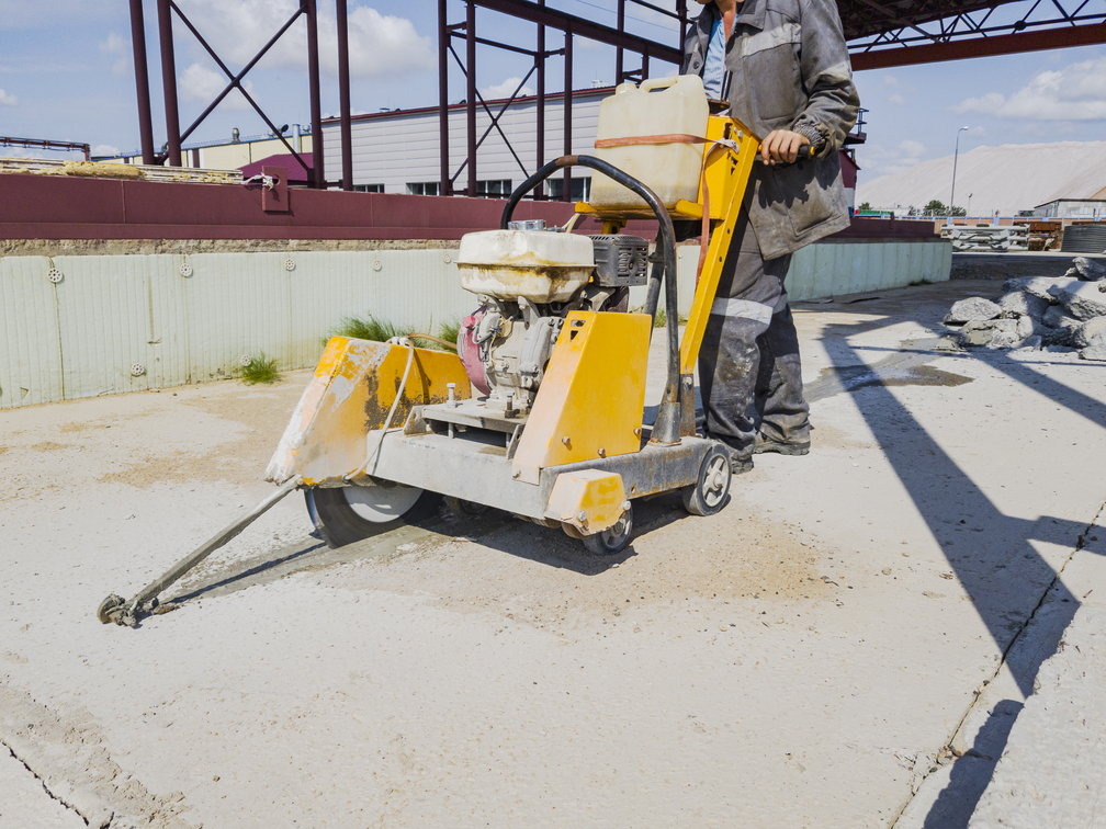 A worker at a construction site cuts concrete with a diamond saw. Concrete breaker. The device of expansion joints